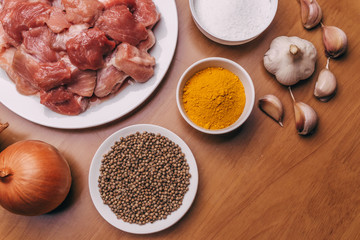 Top view of cooking ingredients on rustic wooden table. Raw meat, onions, garlic