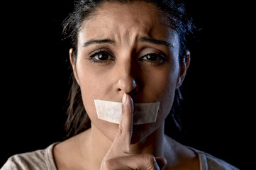 close up portrait of young attractive woman with mouth and lips sealed in adhesive tape restrained