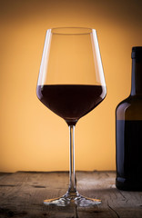Classy glass of wine with bottle of wine on wooden table