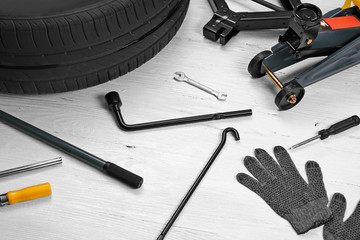 Car wheel with tools on wooden background