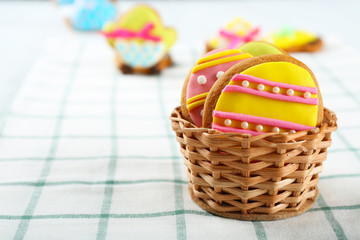 Fototapeta na wymiar Wicker basket with tasty Easter cookies on kitchen table