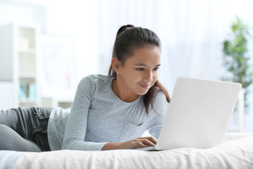Cute girl lying on bed with laptop