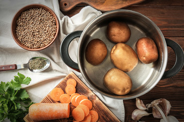 Metal pan with potatoes and other products on table, top view