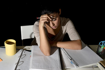 Spanish girl studying tired and bored at home late night looking sad and stressed preparing exam