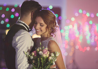 Cute happy wedding couple against defocused lights