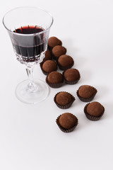 Delicious chocolate truffles and red wine on white background