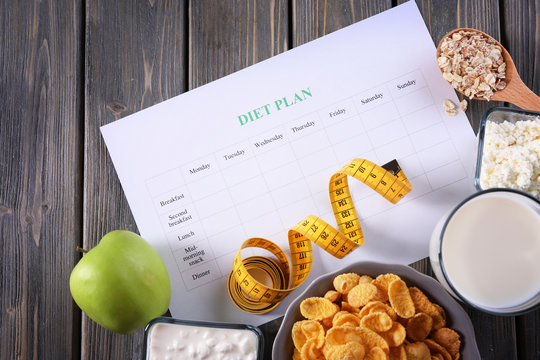 Different products, diet plan and measuring tape on wooden background