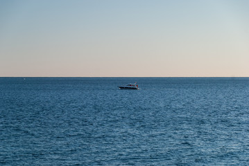 Lonely fishing boat at the open sea at sunset, freedom concept