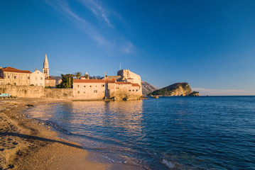 Fototapeta na wymiar Ancient stone buildings by the sea at sunset in old town Budva, Montenegro