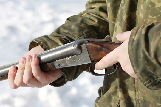 Close-up of a hunter holding his old 16 caliber side-by-side double-barreled shotgun in winter forest