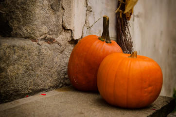 Halloween autumn holiday decoration at the stone stairs. Red pumpkins against grunge wall, seasonal...