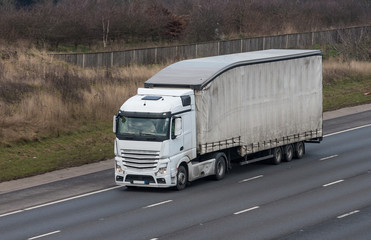 White lorry with high step frame trailer in motion on the motorway
