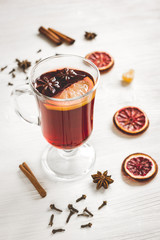 mulled wine with spices in cup on wooden background