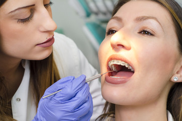 Closeup young female dentist checking young woman braces 