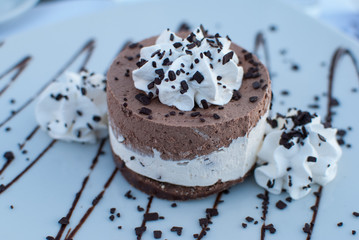 Chocolate cream cake close up, decorated with whipped cream and chocolate syrup 