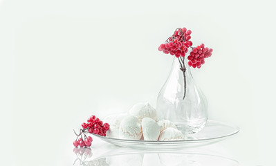 meringue with a branch of viburnum in glass transparent vase still life