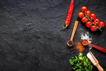 spices in wooden spoon on dark background top view