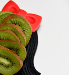 fresh green kiwi fruit slices close up served on decorative black plate on white background top view