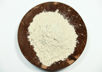 loose cosmetic beauty natural clay powder served in a creative and decorative wooden coconut bowl on white background top view 