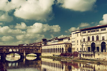 View from the river to the famous italian medieval bridge - Ponte Vecchio in Florence with blue sky and clouds, travel outdoor Italy sightseeing background