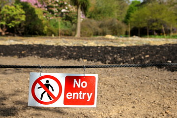 No entry sign hanging in front of some muddy ground