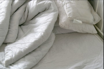 Duvet and pillows on an unmade bed
