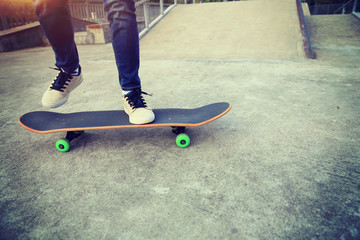 young skateboarder legs riding skateboard at skatepark