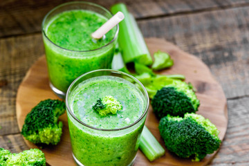 Green vegetable smoothie in glass at wooden background
