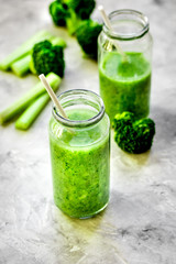Green vegetable smoothie in glass at gray background