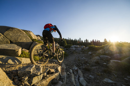 A man rides his mountain bike along the Donner Lake Rim Trail at sunrise near Truckee, California.
