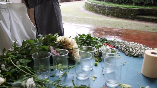 A florist preparing flowers for the wedding catering on a rainy day in Italy, 4K