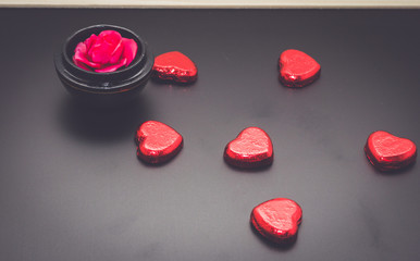 red heart chocolate and rose on blackboard in dark.