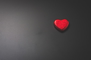 red heart chocolate on blackboard in dark.