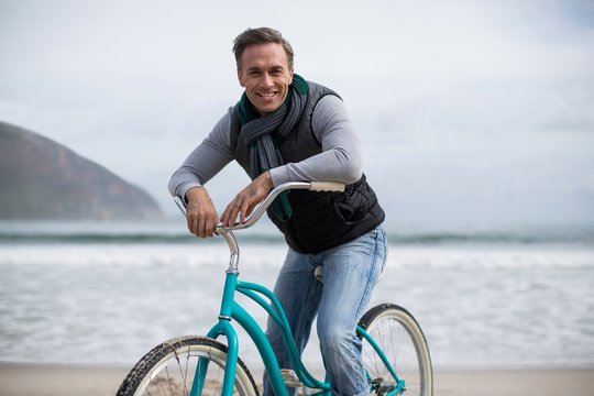 Portrait of mature man riding bicycle on the beach