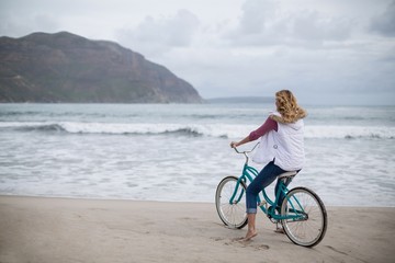 Mature woman riding bicycle on the beach