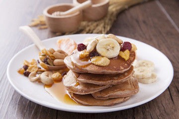 Sweet pancake with banana and serial topping on the wood table in morning light