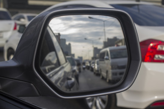 The side view mirror shows many cars get the traffic jam.