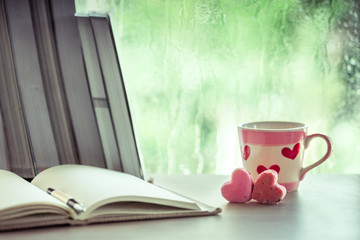 heart pink cookies and coffee cup with notebook on rainy day