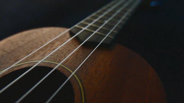 Closeup ukulele guitar tracking from camera on the slider.