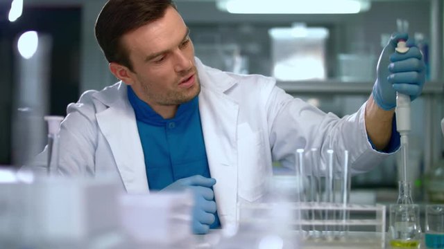 Scientist man using pipette in lab. Researcher with dropper working in laboratory. Scientist student working in lab. Lab worker using laboratory equipment. Laboratory scientist working with pipette