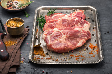 Raw pork steak for grilling on iron tray close up