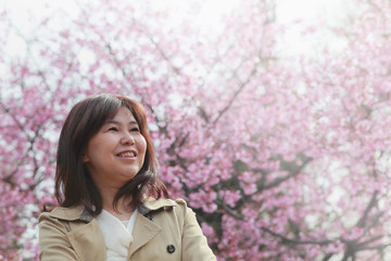満開の桜と笑顔の50代女性