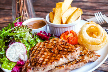 Grilled pork steak with vegetables salad and french fries
