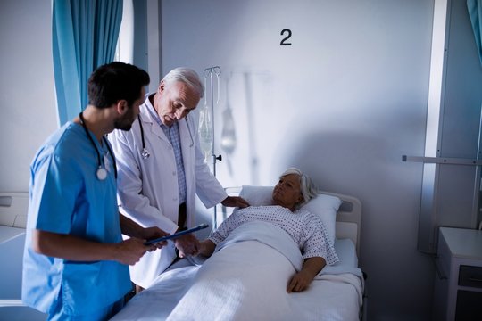 Doctors Comforting Senior Patient On Bed