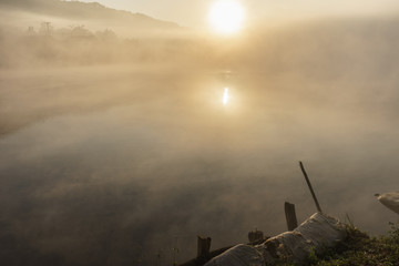 Mist in lake at dawn with clouds reflected in the calm water