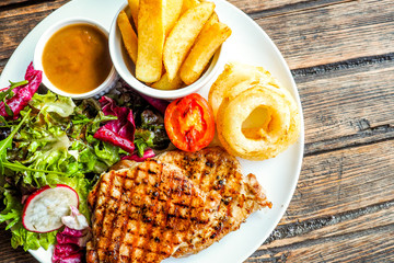 Grilled pork steak with vegetables salad and french fries