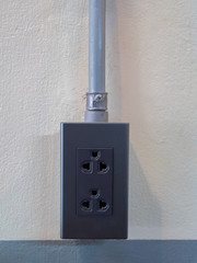 AC power socket, loft style and metal wire pipes on the concrete
