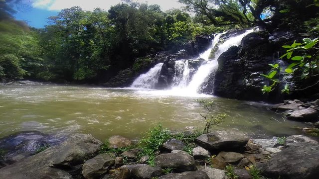 A view of a tropical waterfall in Fiji called Bouma Falls pours into a natural freshwater pool.