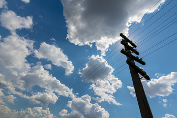 Old telegraph pole, profiled on sky with cumulus clouds, on a bright, sunny, day