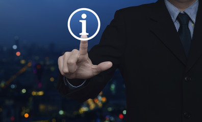 Businessman pressing information sign icon over blur colorful night light city tower background
